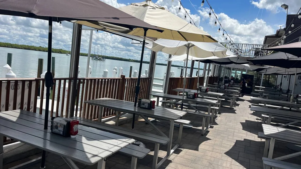 Sailboats moored in the backwater off Marco Island, seen past the dock pilings and picnic tables of the Snook Inn deck.
